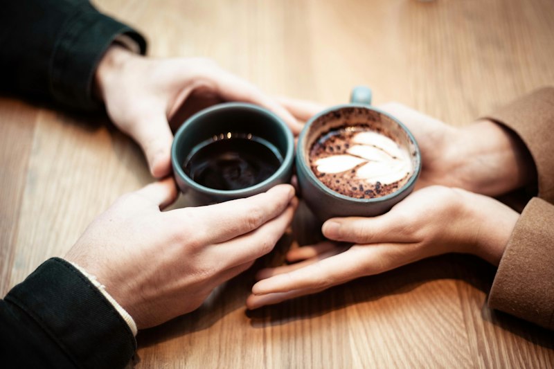 Two people’s hands around their cups of coffee